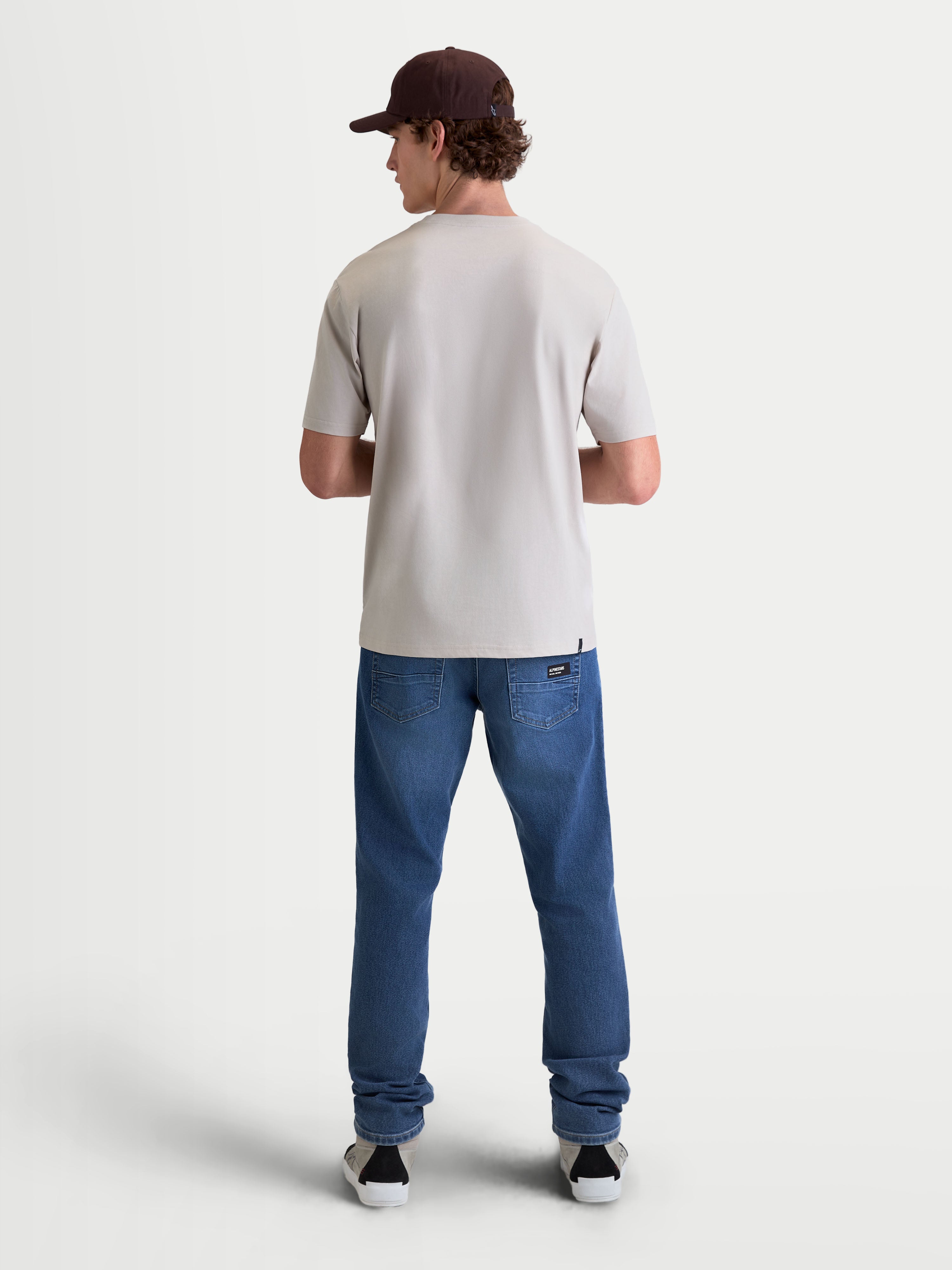 Alpinestars Elliptogrit CSF, camiseta de mangas cortas para hombre en color gris cemento, vista posterior sobre modelo, confeccionada en una mezcla de algodón y poliéster para un estilo casual de ropa deportiva inspirado en el motorsport.