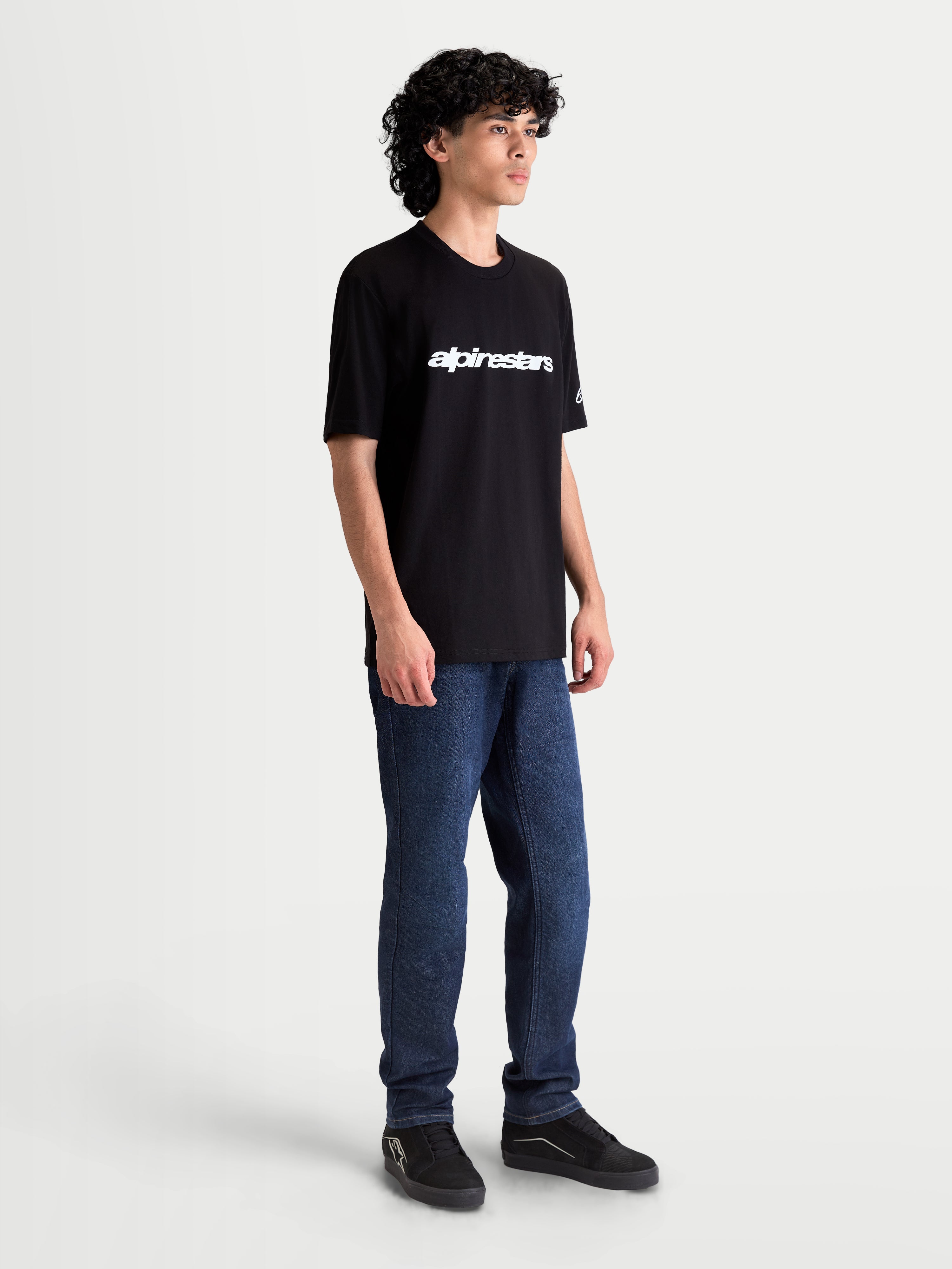 Alpinestars Race Wordmark CSF, camiseta de mangas cortas para hombre y mujer, negra y blanca, con logotipo wordmark frontal blanco y detalle de marca en la manga, vista en modelo, ropa deportiva de estilo motorsport