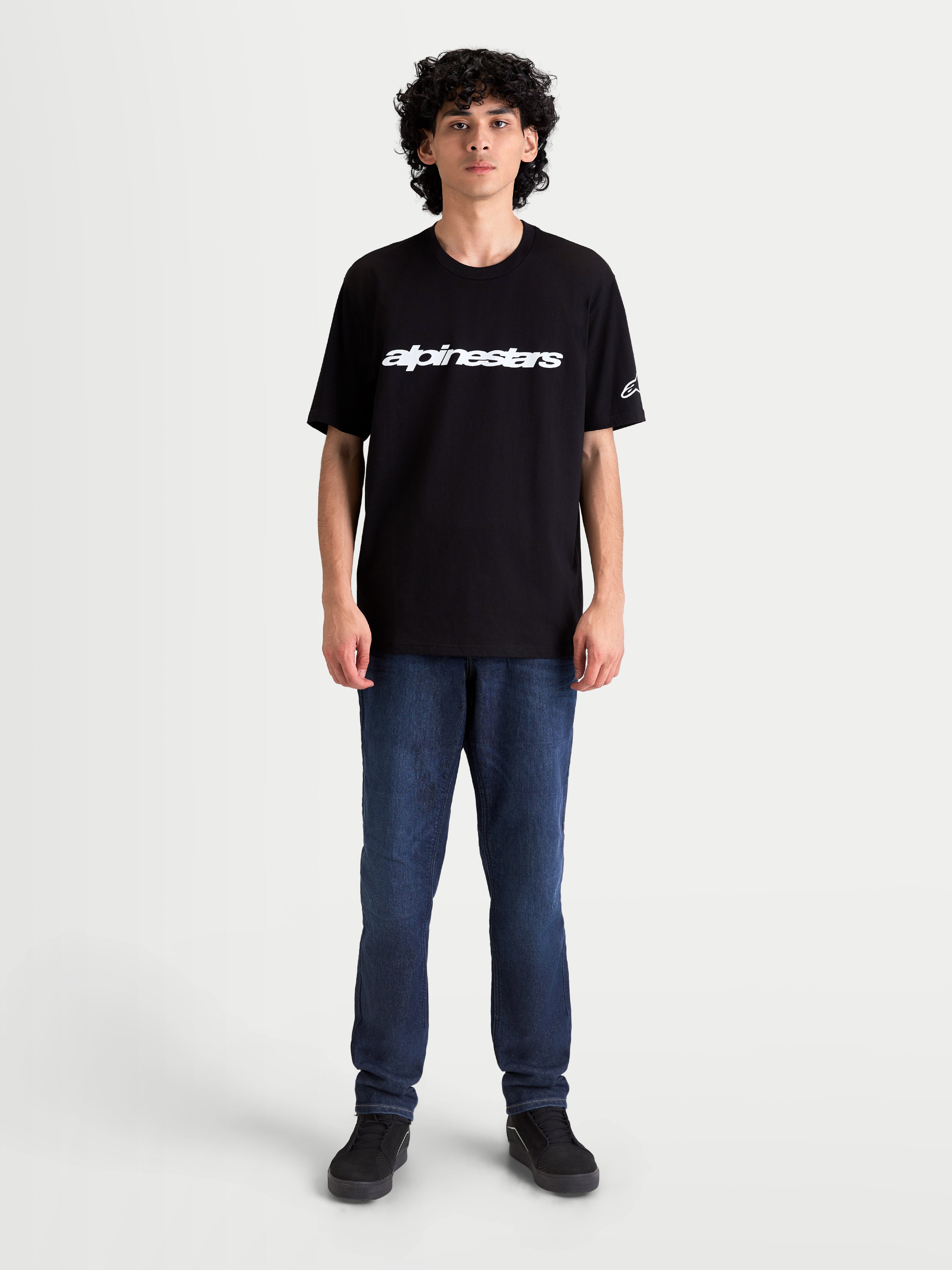 Alpinestars Camiseta Race Wordmark CSF, camiseta de mangas cortas de estilo sportswear casual, negra y blanca, con wordmark frontal de Alpinestars y logotipo Ageless en la manga, vista frontal en modelo
