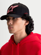 Alpinestars Gorra Lineout, gorra de béisbol negra con visera curva, corona estructurada con logotipo Astars bordado en rojo y blanco, mostrada en un modelo, ropa deportiva