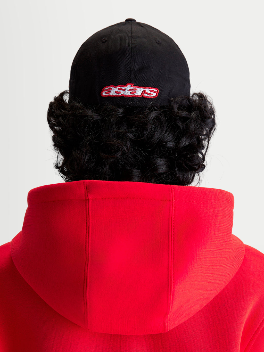 Alpinestars Gorra Lineout, gorra de béisbol de sportswear, negra y roja, vista posterior en modelo con logotipo Astars bordado, corona estructurada y construcción de tejido de sarga