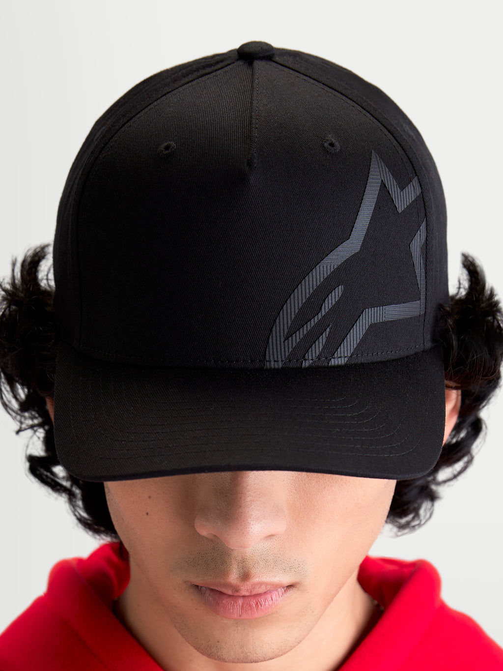 Alpinestars Gorra Maze, gorra de estilo sportswear inspirada en el motorsport, unisex, negra, tejido de sarga con corona estructurada, visera curva y logotipo Astars Corp Shift texturizado en el mismo tono, vista frontal en modelo.
