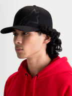 Alpinestars Gorra Maze, gorra de hombre inspirada en el motorsport de color negro, con corona estructurada, visera curva y logotipo Astars Corp Shift texturizado, vista de perfil lateral en modelo.