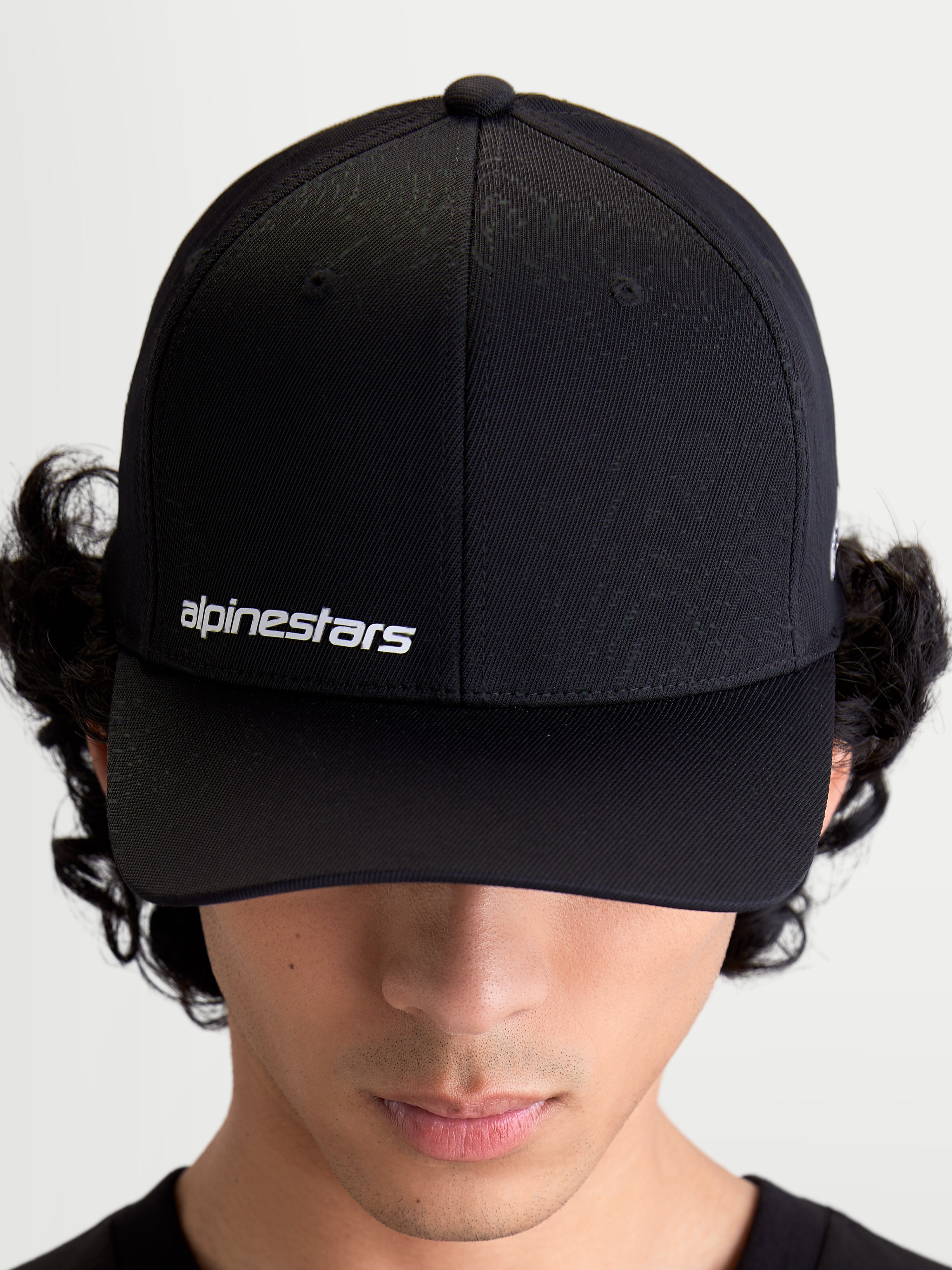 Alpinestars Points Hat, Black Curved Bill Sportswear Cap on Model, featuring White Alpinestars Word Logo on front, Lightweight Nylon Tactel Construction.