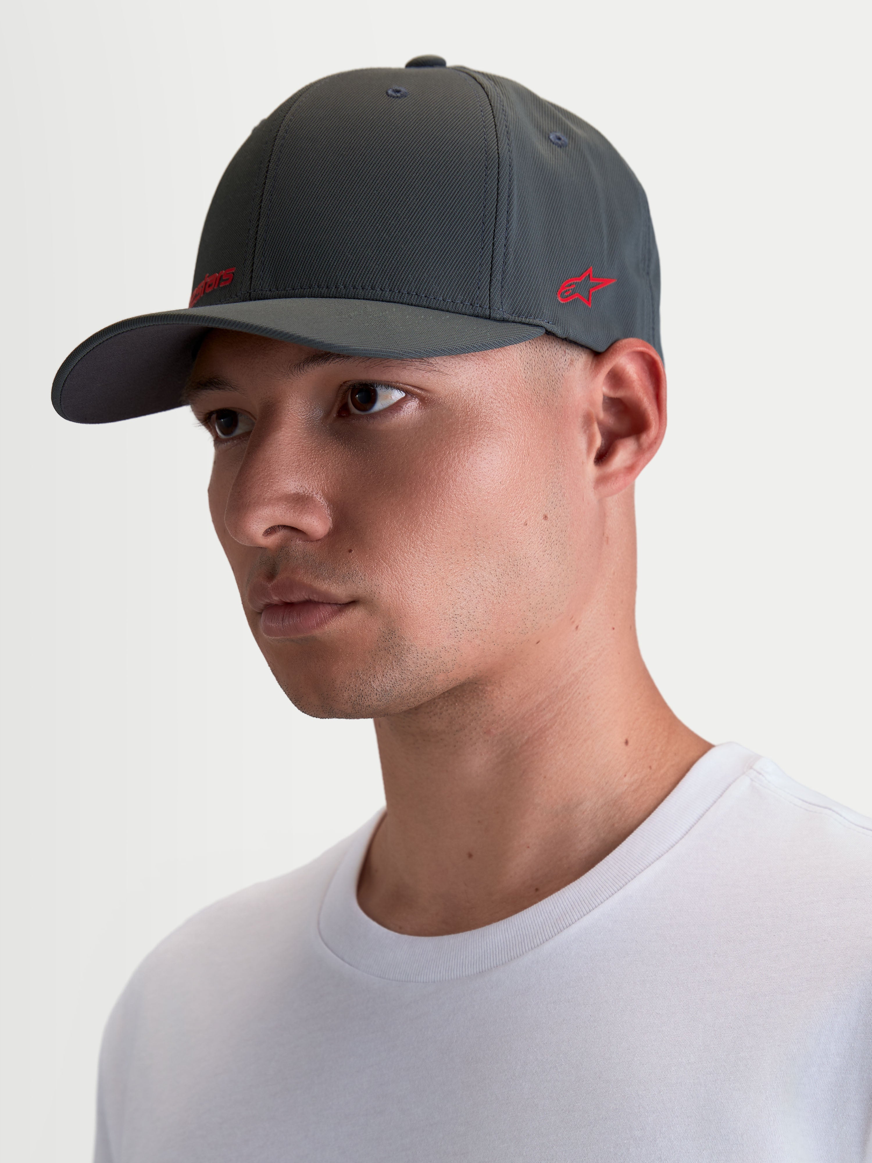 Alpinestars Gorro Points, gorra sportswear de visera curva sobre modelo, gris oscuro con logotipo rojo, nailon tactel ligero, ajuste flex-back para comodidad diaria