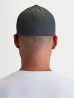 Alpinestars Gorro Points, gorra de estilo sportswear unisex, gris oscuro y rojo, tejido ligero de nylon tactel con ajuste flex-back, vista trasera sobre modelo con logotipo Astars rojo