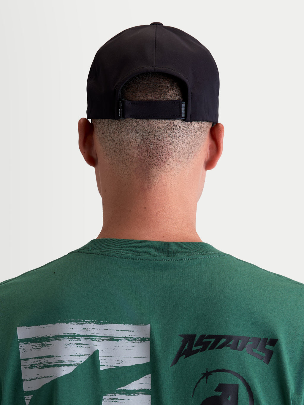 Alpinestars Gorra Algo Perf Ajustable, gorra snapback de motorsport, color negra, vista trasera en modelo con detalle del cierre ajustable, confeccionada en tejido técnico transpirable para uso deportivo y diario, unisex