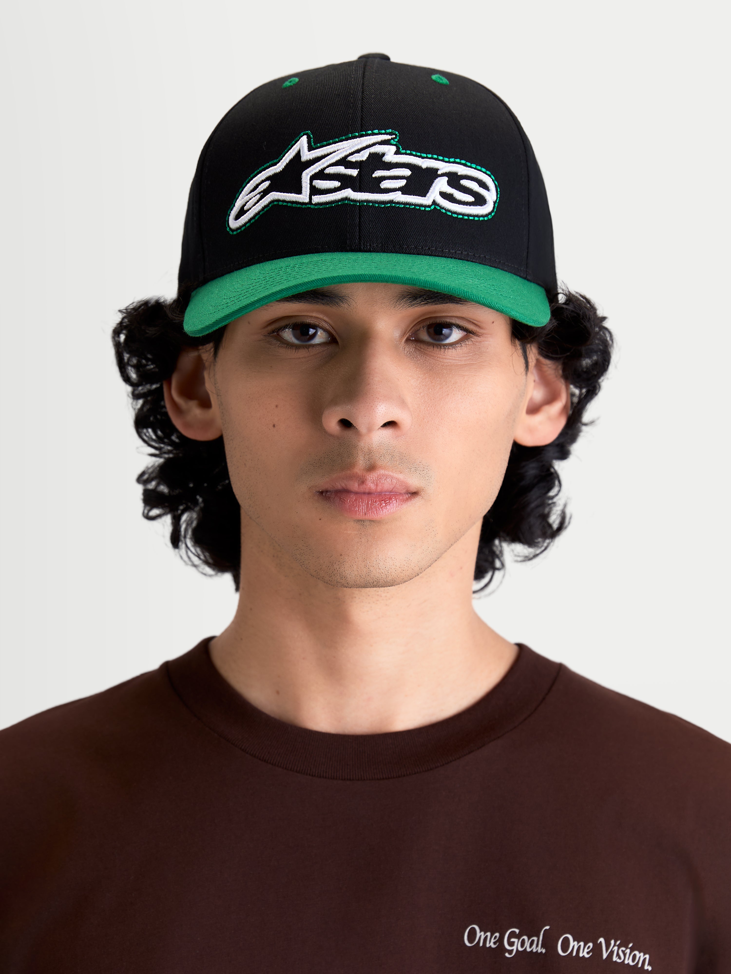 Alpinestars Retro Snapback, gorra de estilo sportswear y lifestyle, negra y verde, con visera curva, corona estructurada y logotipo Astars bordado con pespunte verde, vista frontal en modelo