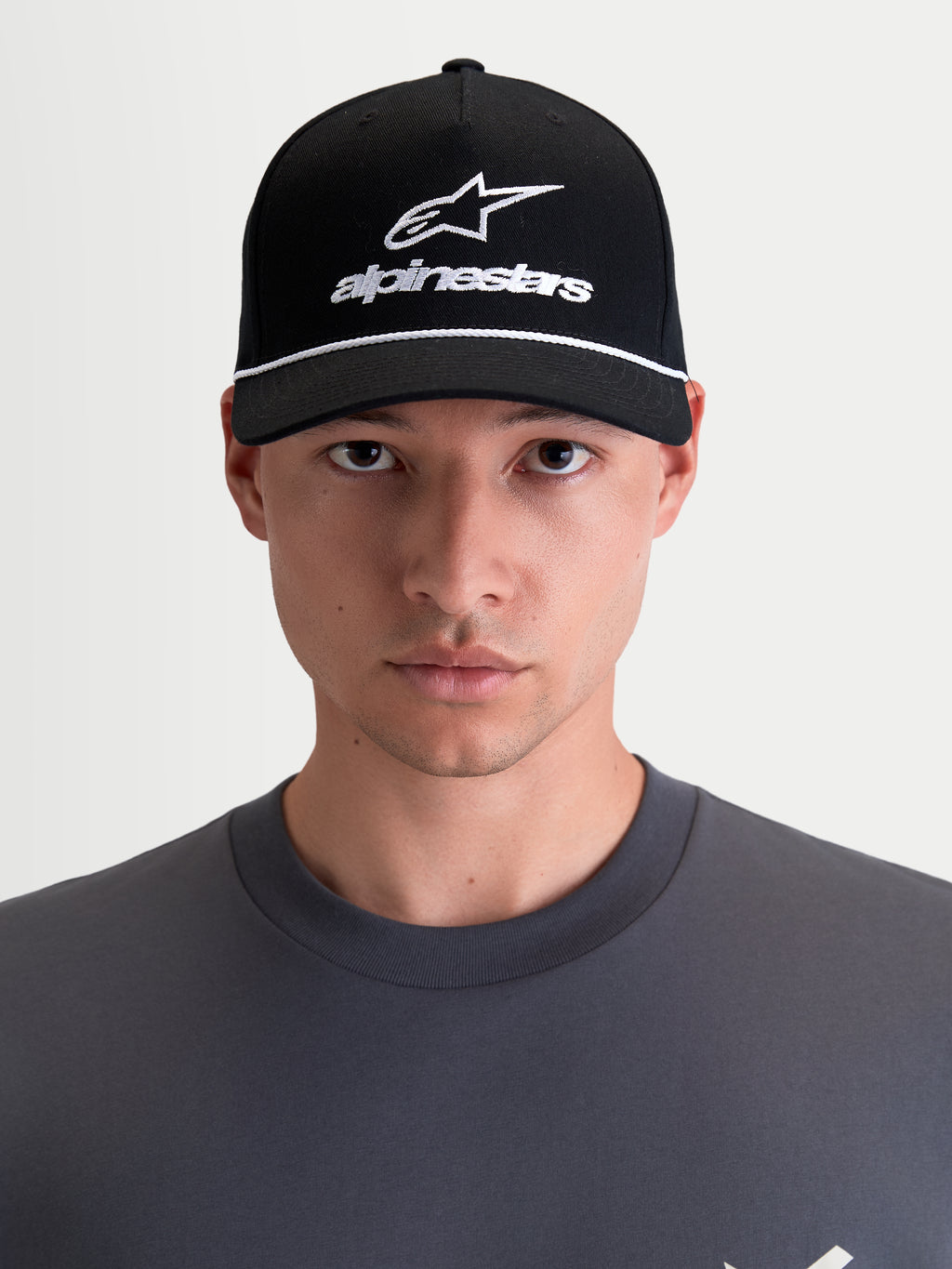 Alpinestars gorra Combo Logo Snapback, gorra sportswear de estilo motorsport, unisex, negra y blanca, con visera curva, corona estructurada y logotipo Astars bordado, sarga de 100% algodón, vista frontal en modelo.