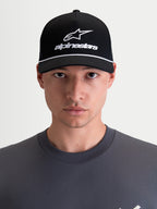 Alpinestars gorra Combo Logo Snapback, gorra sportswear de estilo motorsport, unisex, negra y blanca, con visera curva, corona estructurada y logotipo Astars bordado, sarga de 100% algodón, vista frontal en modelo.