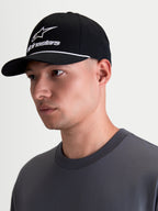 Alpinestars Gorra Combo Logo Snapback, gorra de ropa deportiva estilo lifestyle, negra y blanca, con visera curva, corona estructurada, bordado blanco y detalle de cordón, mostrada en un modelo de perfil.