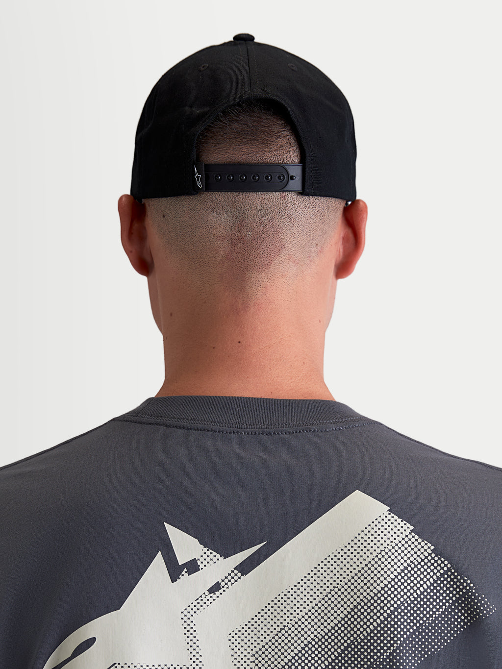 Alpinestars Gorra Combo Logo Snapback, gorra de estilo motorsport para hombre y mujer, negra, confeccionada en sarga de algodón duradera, vista trasera en modelo que muestra el cierre snapback ajustable y un pequeño logotipo blanco.