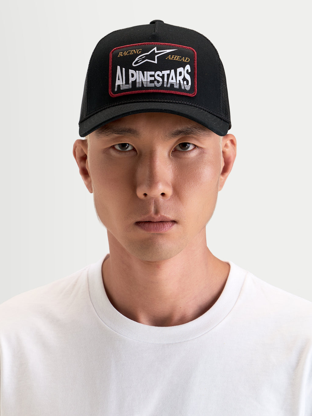 Alpinestars Gorra Hemmings Trucker, gorra deportiva negra con visera curvada y malla transpirable, con parche tejido con logotipo frontal, vista frontal en modelo