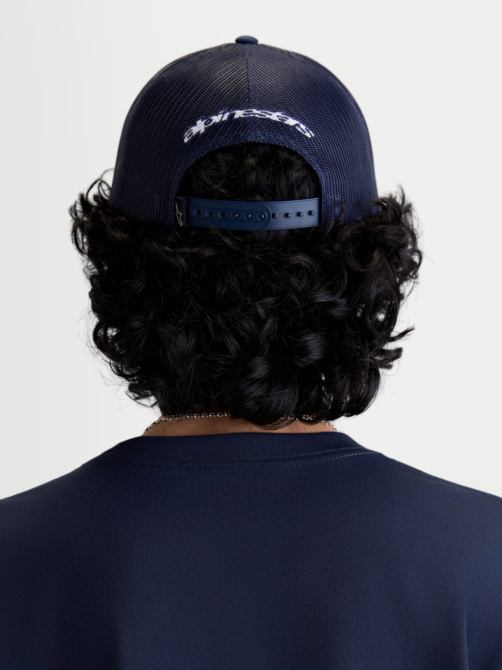 Alpinestars Gorra Meteorite, gorra de estilo casual, azul marino, paneles de malla trasera y cierre snapback ajustable, marca Alpinestars bordada en blanco, vista trasera sobre modelo.
