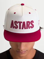 Alpinestars Stadium Snapback, gorra de visera plana estilo sportswear, blanca y roja, con aplique frontal del logotipo ASTARS, costuras en contraste y corona estructurada, mostrada en modelo