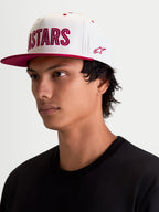 Alpinestars Gorra Stadium Snapback, gorra de estilo de vida sportswear, blanca y roja, con visera plana, corona estructurada, aplique frontal del logotipo Astars con costuras en contraste y bordado lateral, vista en modelo