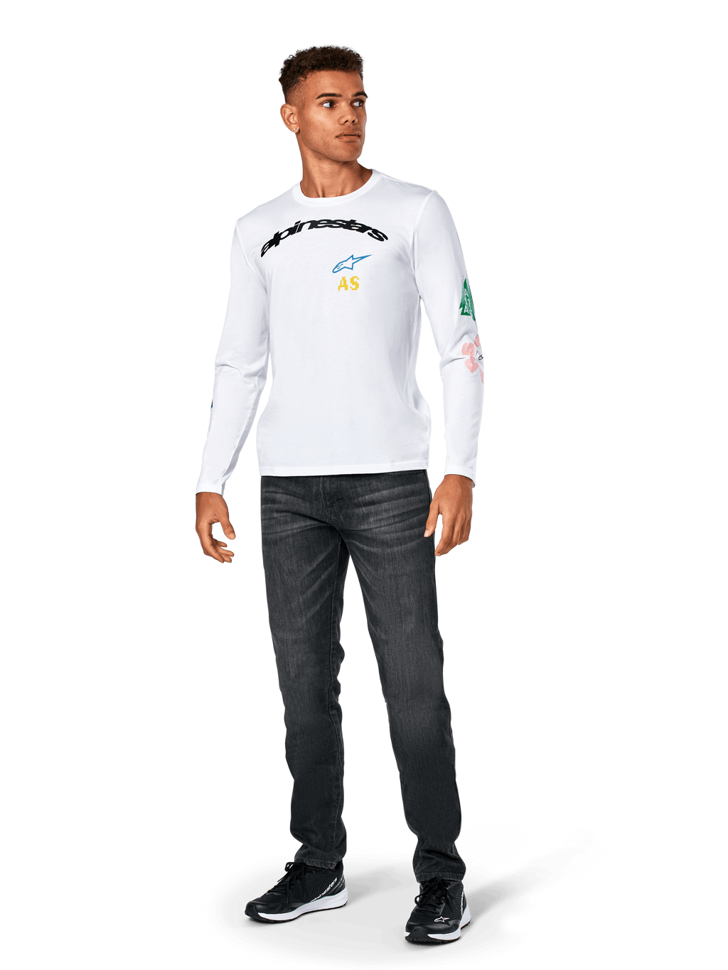 Alpinestars Brundo CSF Tee - Manga Larga, blanca, ropa deportiva casual, con el texto 'alpinestars' en negro en el pecho, un logotipo de estrella azul e iniciales 'AS' amarillas, gráficos coloridos en la manga, combinada con vaqueros oscuros y zapatillas negras