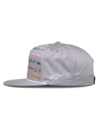 Gorra Glphy de Alpinestars, gorra snapback gris, vista lateral, visera plana con ribete de cuerda blanca, con impresión de logotipos multicolor en la parte frontal y logotipo bordado blanco en el lateral, estilo urbano motorsport casual