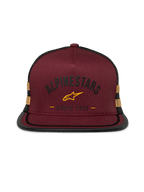 Gorra Trucker Alpinestars Backline, visera plana con cierre snapback, frontal de sarga rojo ladrillo con malla trasera negra, logotipo y franjas laterales en amarillo mostaza, copa estructurada con ribete de sutache en la visera, estilo casual motorsport streetwear