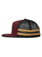 Gorra Trucker Alpinestars Backline, vista de perfil lateral, colores granate, negro y mostaza, frontal de sarga granate con panel trasero de malla negra, con franjas horizontales mostaza en el lateral, visera plana con ribete negro, gorra snapback casual de inspiración motorsport