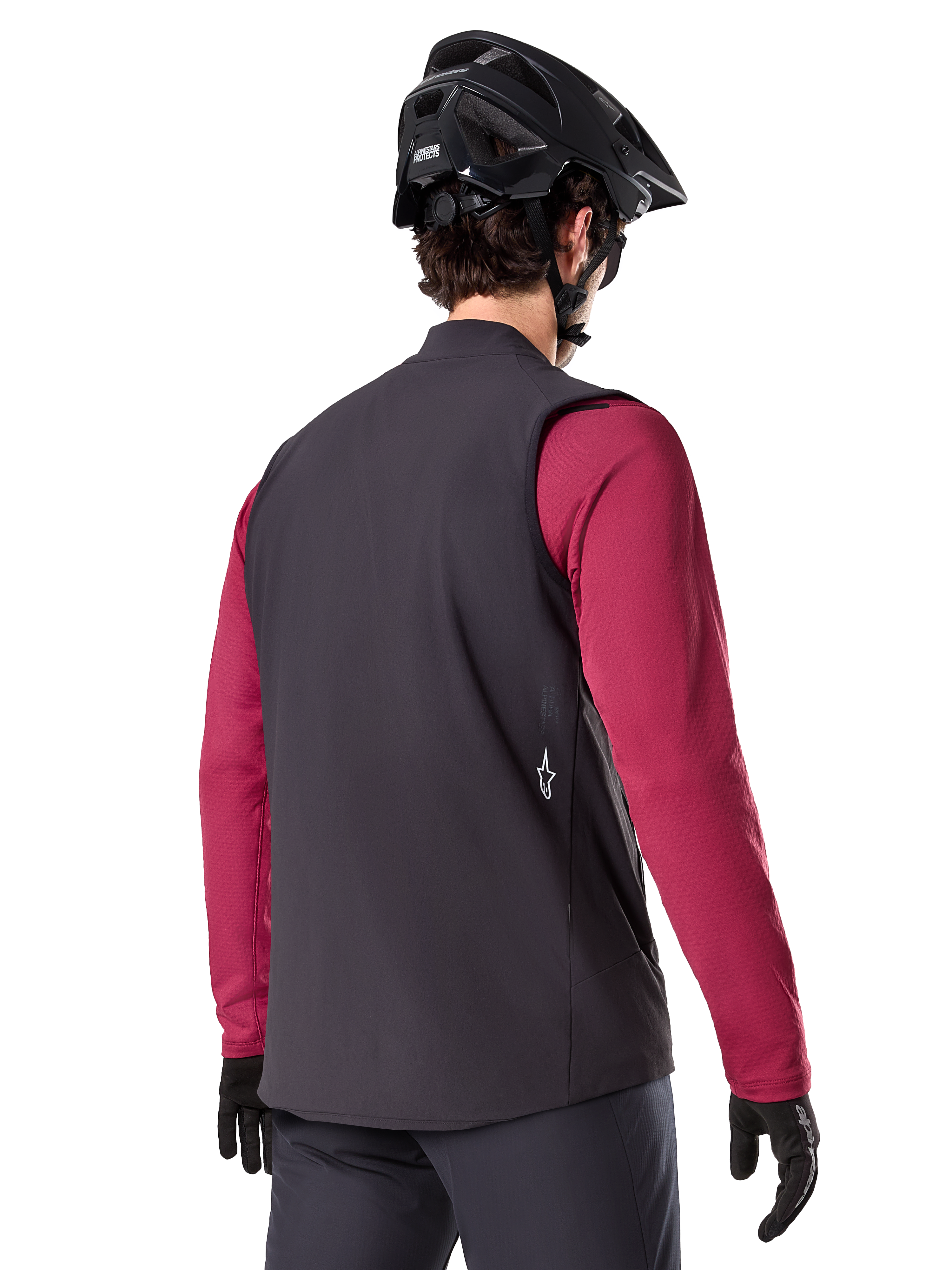 Chaleco térmico Alpinestars A-Dura, negro, vista trasera, puesto sobre un jersey granate de manga larga con casco y guantes negros de MTB, equipamiento de ciclismo ligero y aislado para rutas todoterreno