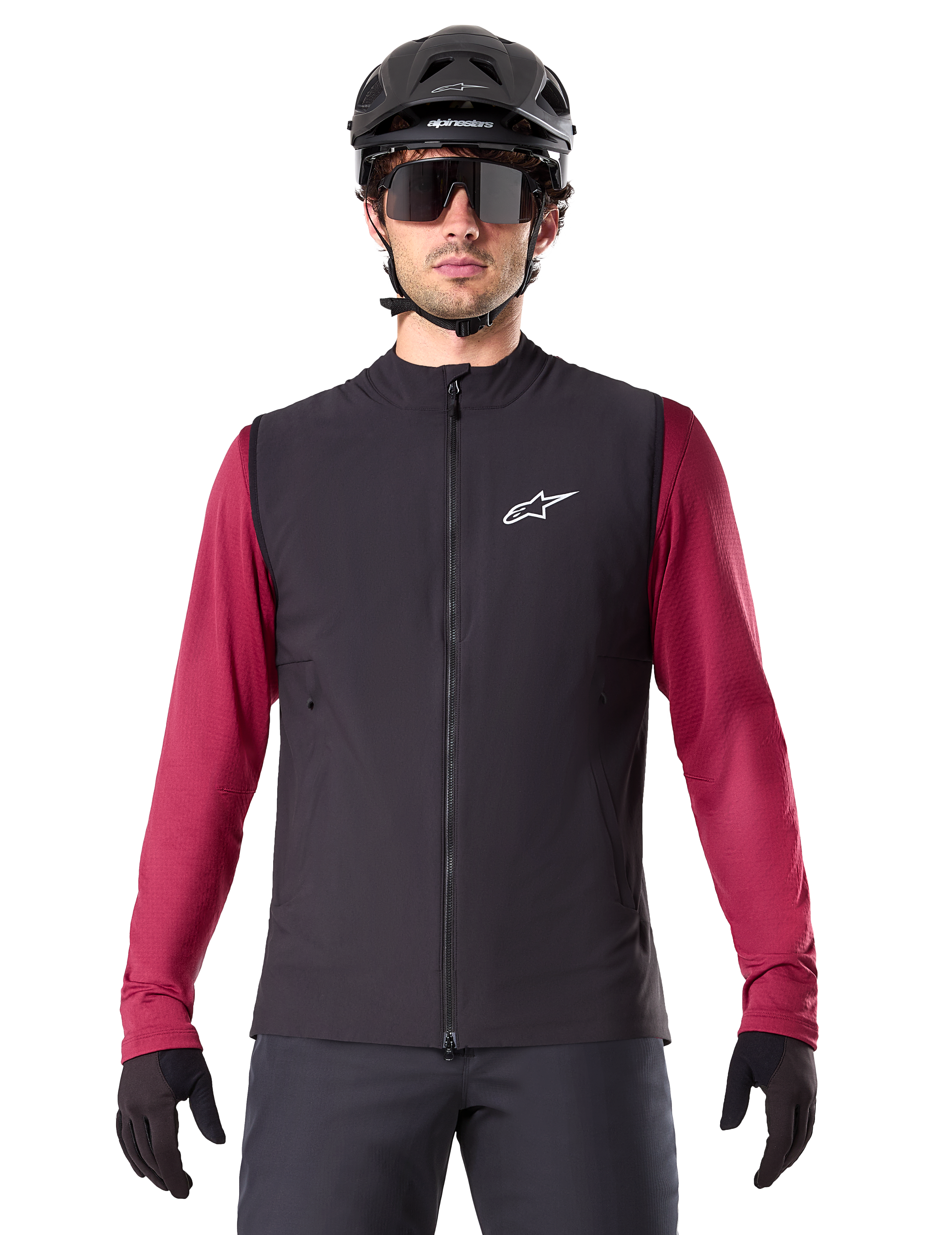 Alpinestars A-Dura Thermal Vest, chaleco de ciclismo térmico negro, usado por un modelo con un jersey granate de manga larga, casco de MTB negro y gafas de sol, con un logotipo blanco en el pecho, protección térmica ligera para ciclismo de montaña
