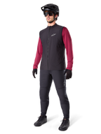 Chaleco Térmico Alpinestars A-Dura, chaleco de ciclismo negro, usado por un ciclista sobre un jersey de manga larga granate y pantalones negros, con casco de MTB y guantes negros, diseñado para ciclismo de montaña en climas fríos