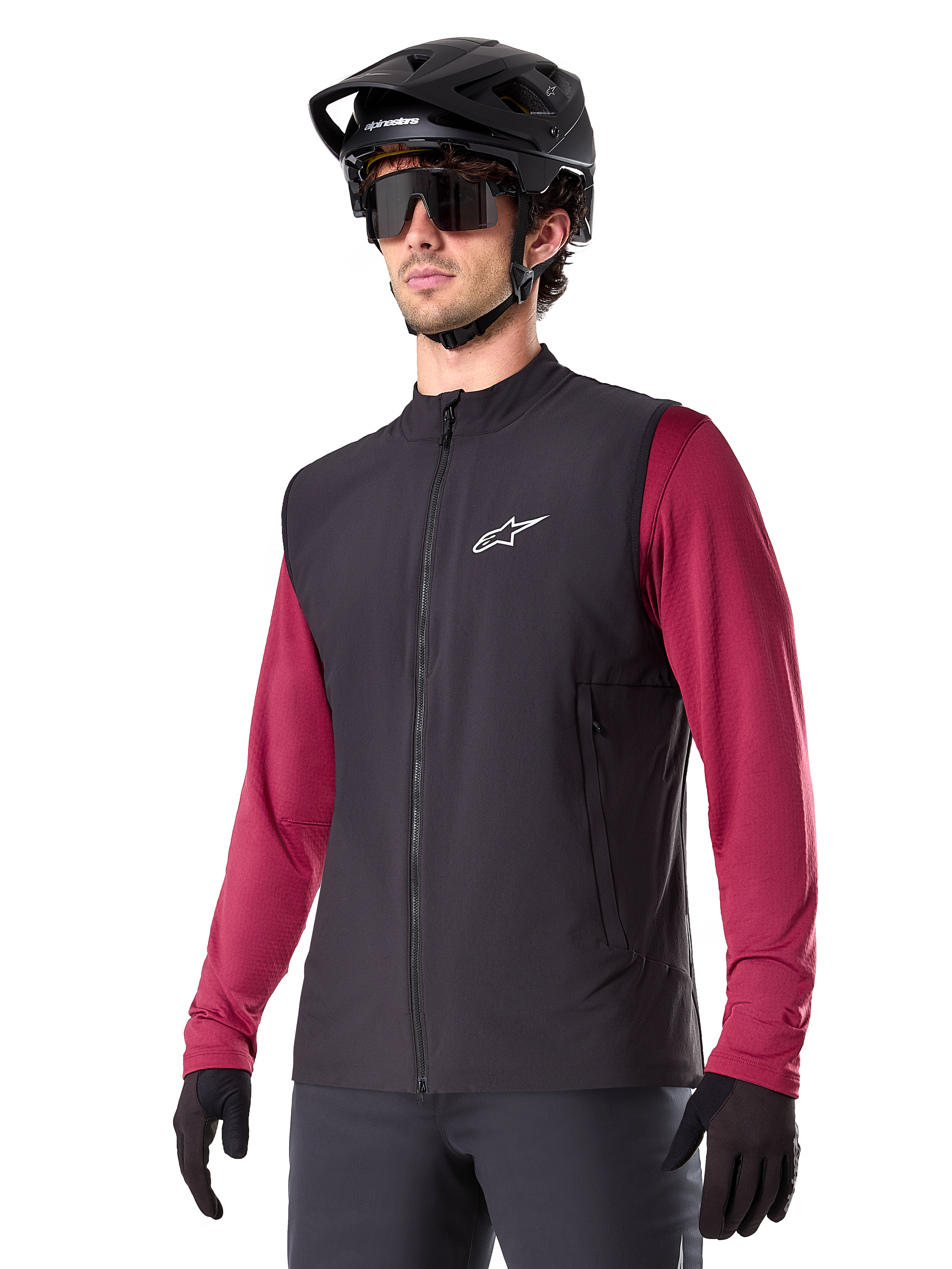 Alpinestars A-Dura Thermal Vest, chaleco térmico de ciclismo negro, usado sobre una camiseta de manga larga granate, con logotipo blanco en el pecho, combinado con casco de MTB negro y gafas de sol, capa de rendimiento con aislamiento para ciclismo de montaña
