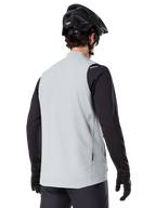 Chaleco térmico Alpinestars A-Dura, Gris Titanio, vista posterior del modelo con jersey de manga larga negro y casco de MTB, diseño minimalista con logo de estrella roja en la espalda, chaleco de ciclismo ligero y aislado para ciclismo de montaña