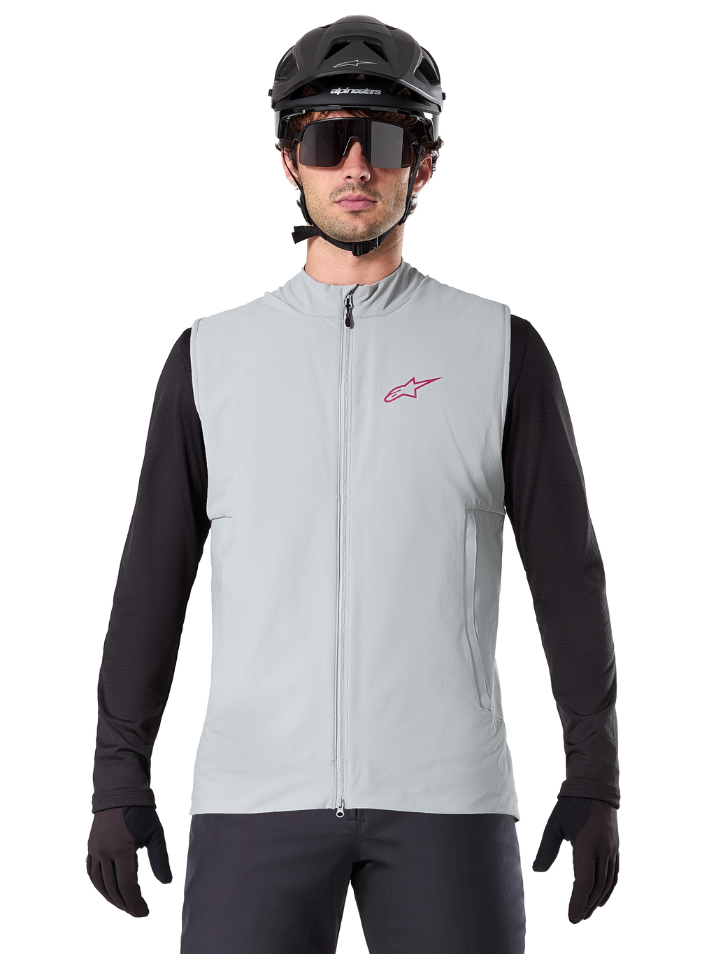 Chaleco Térmico Alpinestars A-Dura, chaleco de ciclismo, gris titanio, usado con un jersey negro de manga larga y casco de ciclismo negro, logo de estrella Alpinestars rojo en el pecho, ligero y con aislamiento para ciclismo de montaña