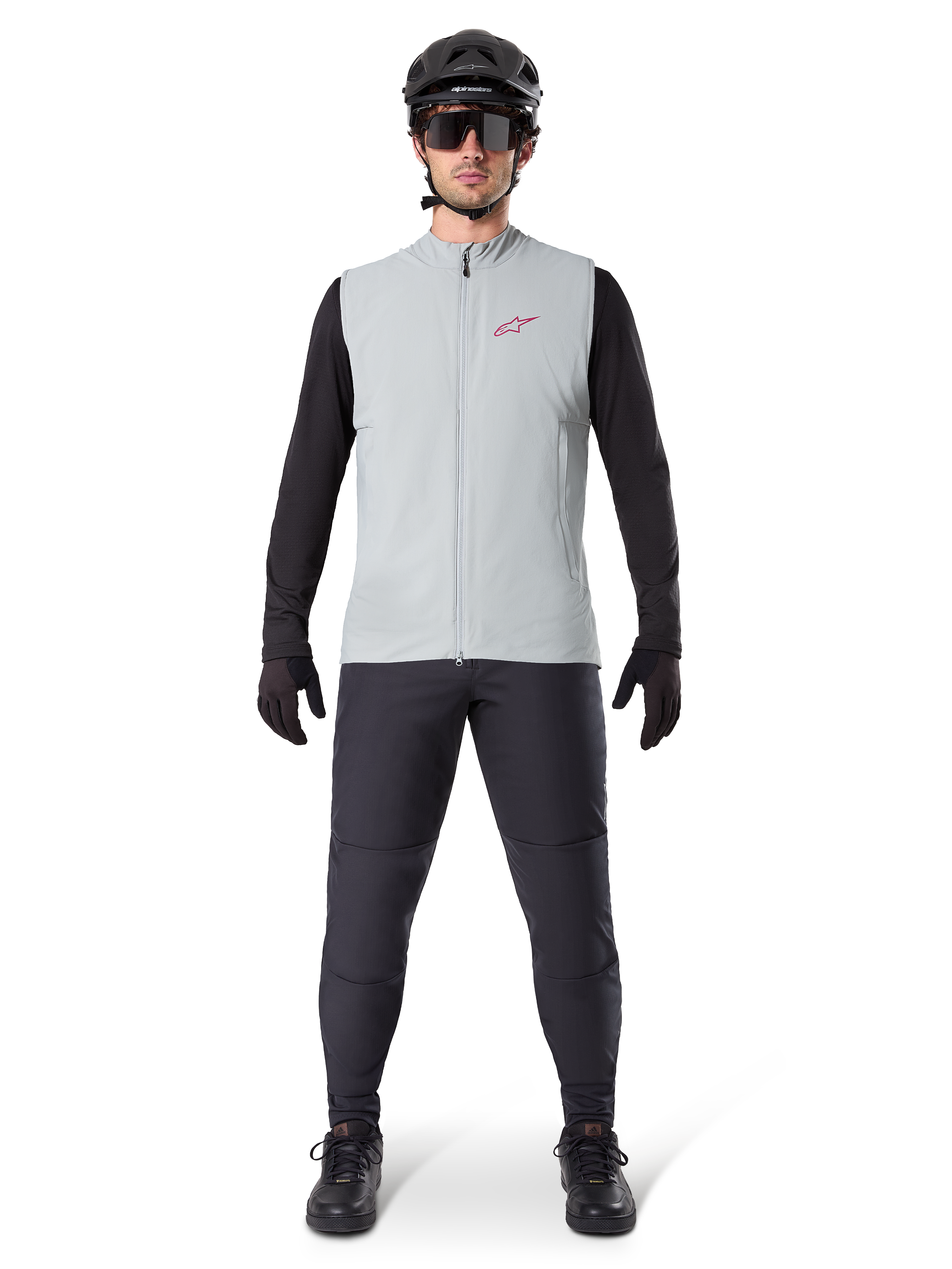 Chaleco térmico Alpinestars A-Dura, chaleco de ciclismo, Gris Titanio, combinado con jersey negro de manga larga y pantalones negros, casco y gafas de sol negros, con logotipo de Alpinestars en rojo, aislamiento térmico ligero para ciclismo de montaña