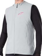 Chaleco térmico Alpinestars A-Dura, chaleco de ciclismo con aislamiento en gris titanio, con logotipo de estrella rosa en el pecho, usado sobre una prenda negra de manga larga, incluye bolsillo vertical con cremallera y cremallera frontal completa, diseñado para rutas de ciclismo de montaña en climas fríos.