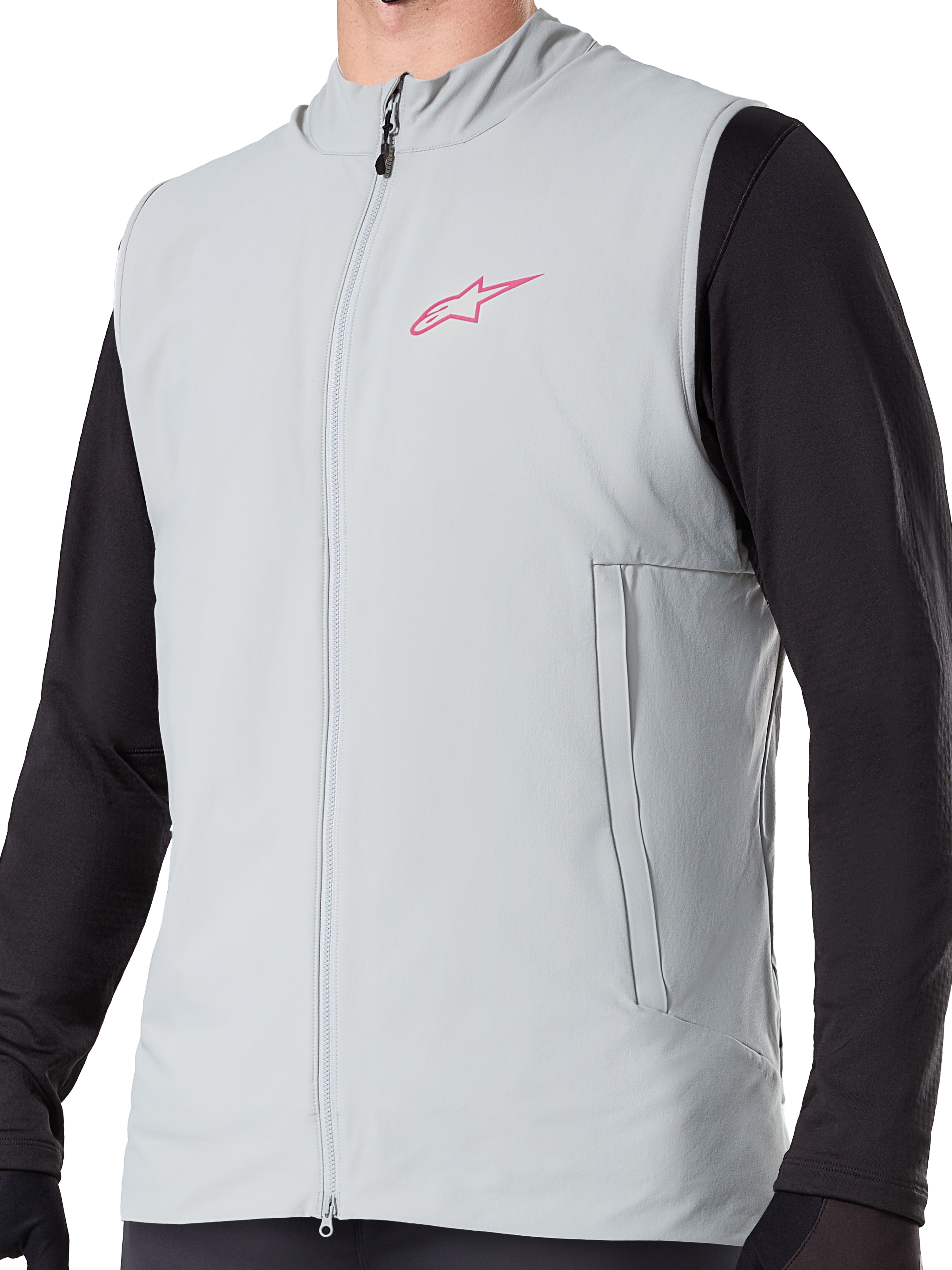 Chaleco térmico Alpinestars A-Dura, chaleco de ciclismo con aislamiento en gris titanio, con logotipo de estrella rosa en el pecho, usado sobre una prenda negra de manga larga, incluye bolsillo vertical con cremallera y cremallera frontal completa, diseñado para rutas de ciclismo de montaña en climas fríos.