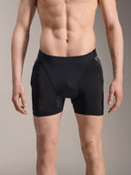 Alpinestars Boxers de Protección A-Motion Plasma, pantalones cortos de protección para MTB, negros con detalles de camuflaje negro, vista frontal en modelo masculino, con malla elástica transpirable y protección de cadera integrada para el rendimiento en ciclismo.
