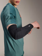 Manga de codo Alpinestars A-Motion Plasma, protector de codo para ciclismo, negro, usado por un ciclista con jersey verde azulado, con el logotipo de Alpinestars y la marca Nucleon Plasma, diseño estilizado y transpirable para protección de MTB