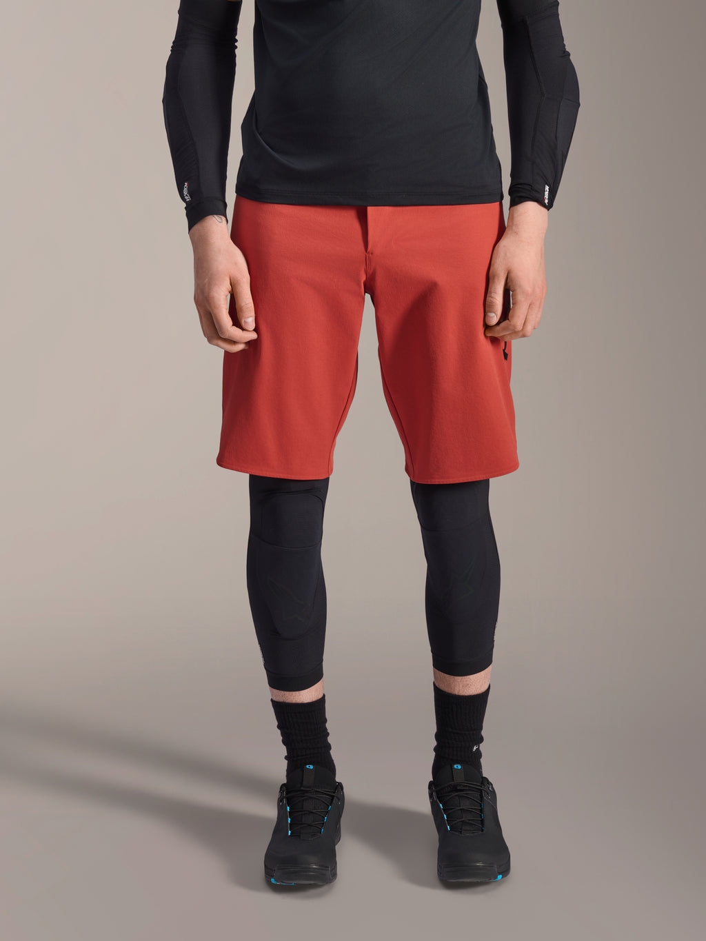Alpinestars A-Motion Plasma Knee Sleeve, protector de rodilla de MTB negro, usado con pantalones cortos rojos y camiseta negra de manga larga, diseño ergonómico de perfil delgado, construcción de malla ligera para conducción fuera de carretera