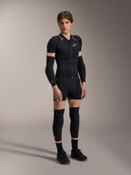 Modelo masculino luciendo la chaqueta protectora de manga corta Alpinestars A-Motion PLASMA, Black Camo con hombros con patrón gris, cremallera frontal central y logotipo blanco en el pecho, combinada con protectores de brazos y rodillas negros, equipo de protección técnico de MTB para conducción todoterreno