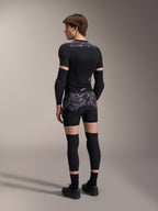 Modelo con boxers de protección Alpinestars A-Motion Plasma en Black Camo y chaqueta de protección A-Motion Plasma a juego, vista trasera que muestra el patrón de camuflaje gris, coderas, rodilleras y zapatillas de ciclismo, equipo completo de protección para bicicleta de montaña