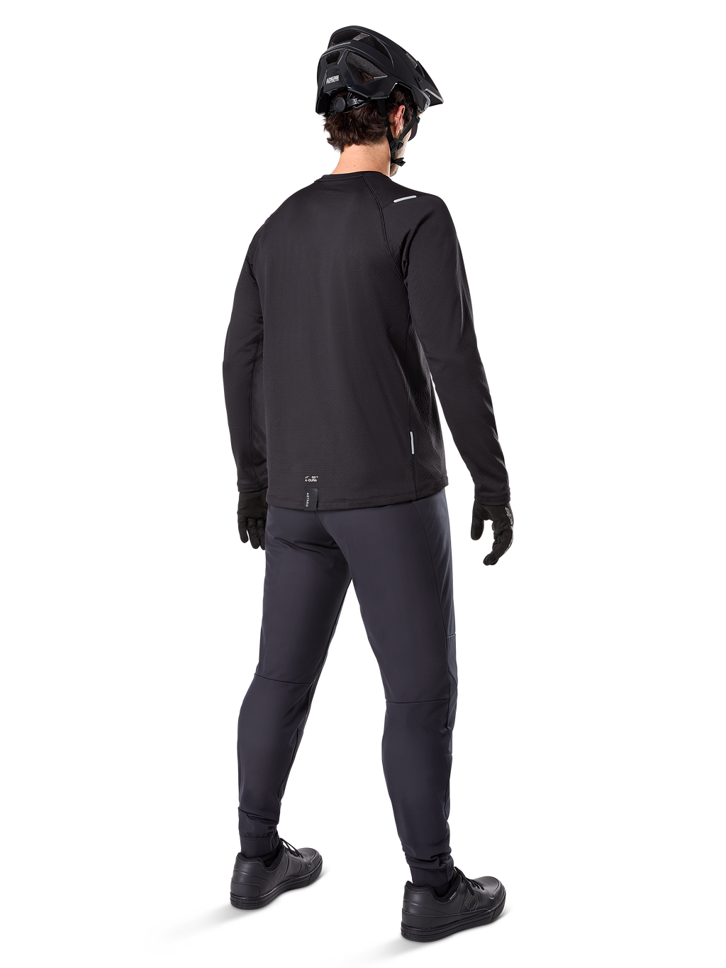 Alpinestars A-Dura Thermal Pant, pantalones de ciclismo de montaña, negro, vista desde una perspectiva trasera con un jersey de manga larga a juego, casco de MTB negro y guantes, equipamiento técnico de ciclismo para clima frío