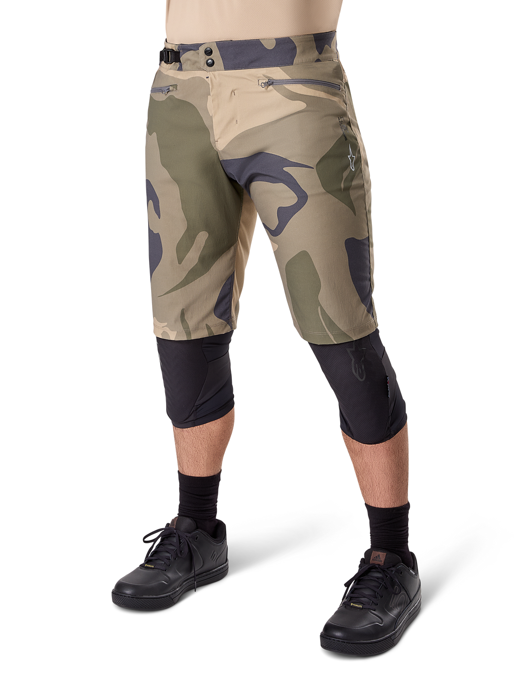Alpinestars A-Dura Camo Liner Short, shorts de ciclismo de montaña, estampado de camuflaje marrón, vista frontal con bolsillos con cremallera y ajustadores laterales en la cintura, usados con rodilleras negras y zapatillas de ciclismo negras, equipamiento duradero para MTB