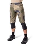 Alpinestars A-Dura Camo Liner Short, shorts de ciclismo de montaña, estampado de camuflaje marrón, vista frontal con bolsillos con cremallera y ajustadores laterales en la cintura, usados con rodilleras negras y zapatillas de ciclismo negras, equipamiento duradero para MTB