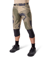 Alpinestars A-Dura Camo Liner Short, shorts de ciclismo de montaña, estampado de camuflaje marrón, vista frontal con bolsillos con cremallera y ajustadores laterales en la cintura, usados con rodilleras negras y zapatillas de ciclismo negras, equipamiento duradero para MTB
