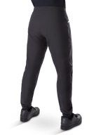 Pantalones impermeables Alpinestars A-Dura, pantalones de mountain bike, negro, vista trasera con zapatillas negras, con membrana duradera de 3 capas, ajuste regular y puños elásticos para ciclismo de montaña