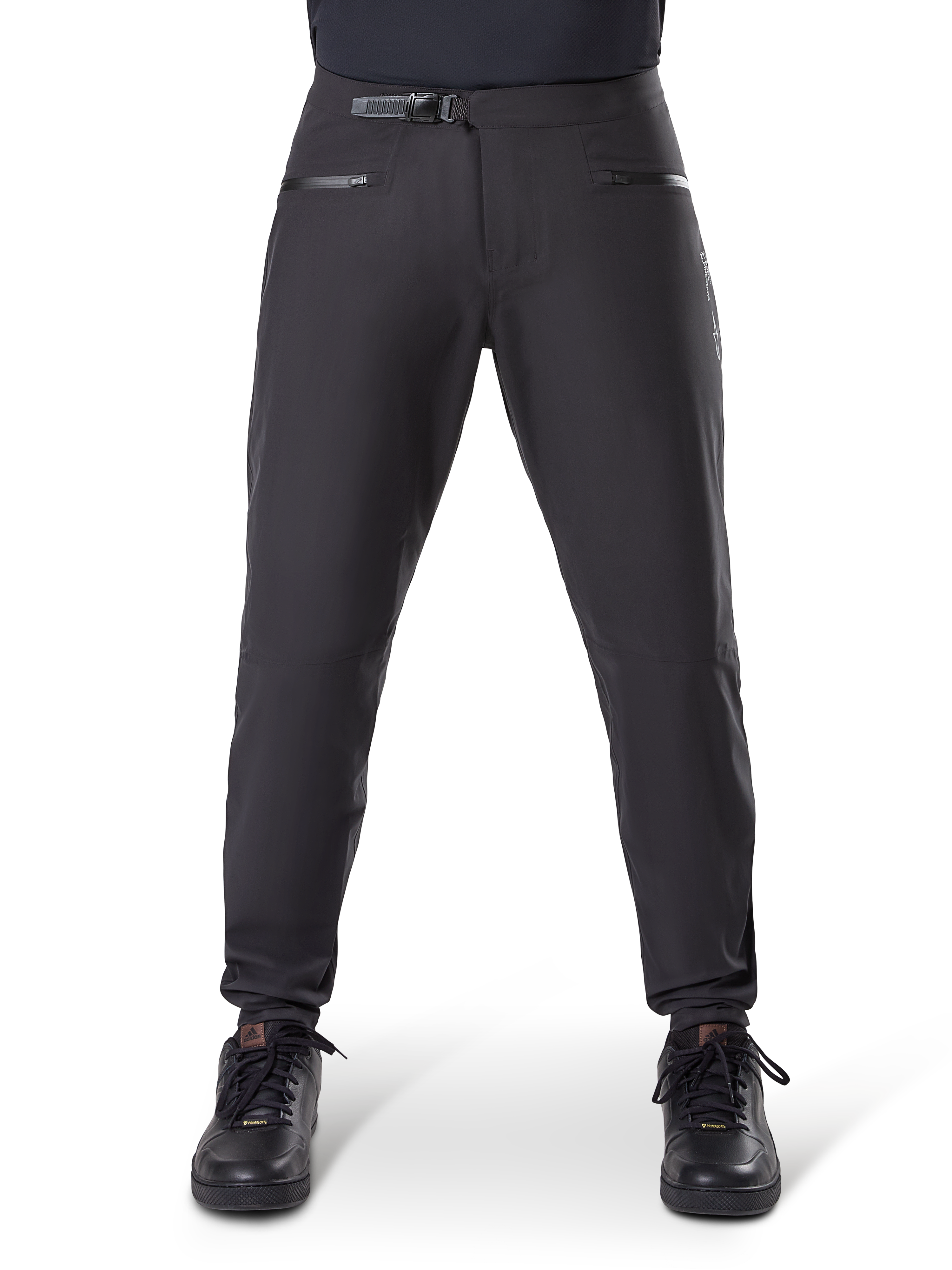Pantalones impermeables Alpinestars A-Dura, negro, pantalones de ciclismo de montaña con cierre de trinquete en la cintura y bolsillos con cremallera, vista frontal en modelo con zapatillas negras, equipo impermeable duradero para MTB