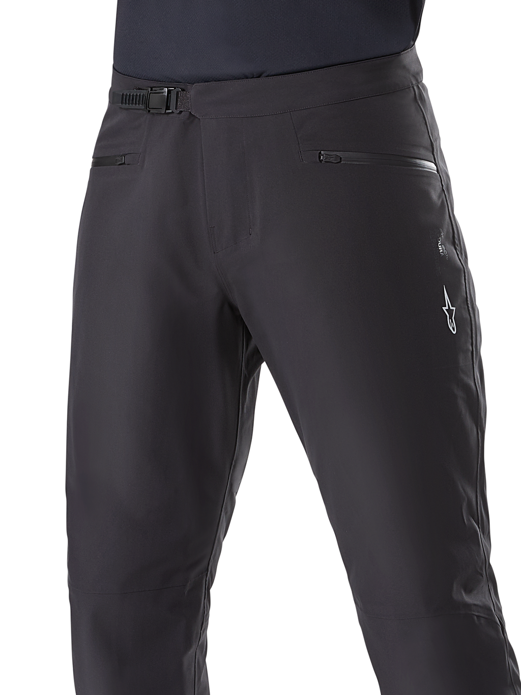 Pantalones Impermeables Alpinestars A-Dura, pantalones de ciclismo de montaña, negros, primer plano de la cintura que muestra el sistema de cierre de trinquete y los bolsillos con cremallera, con el logotipo blanco de Alpinestars en el muslo, tejido duradero para rutas con clima húmedo