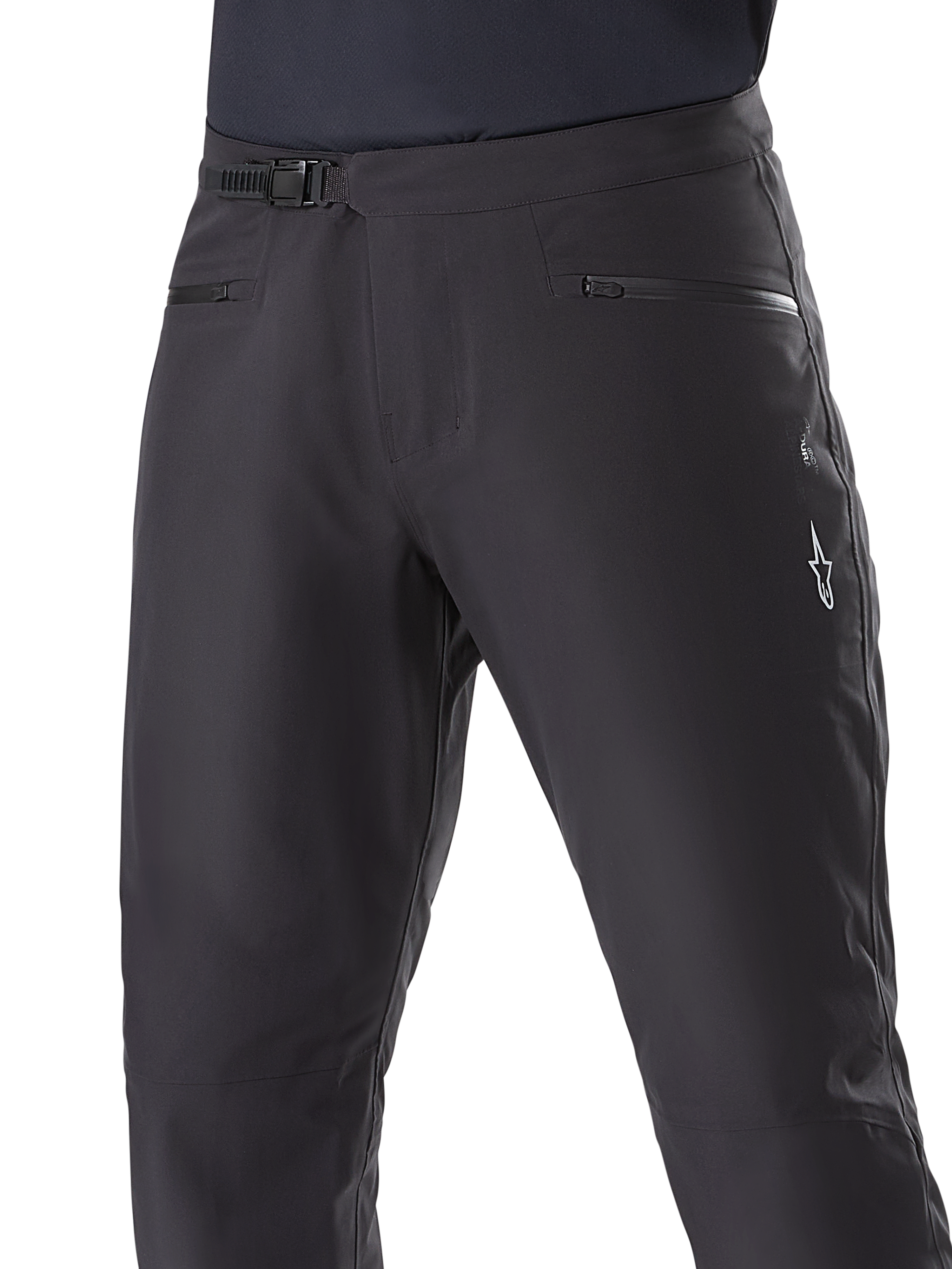 Pantalones Impermeables Alpinestars A-Dura, pantalones de ciclismo de montaña, negros, primer plano de la cintura que muestra el sistema de cierre de trinquete y los bolsillos con cremallera, con el logotipo blanco de Alpinestars en el muslo, tejido duradero para rutas con clima húmedo