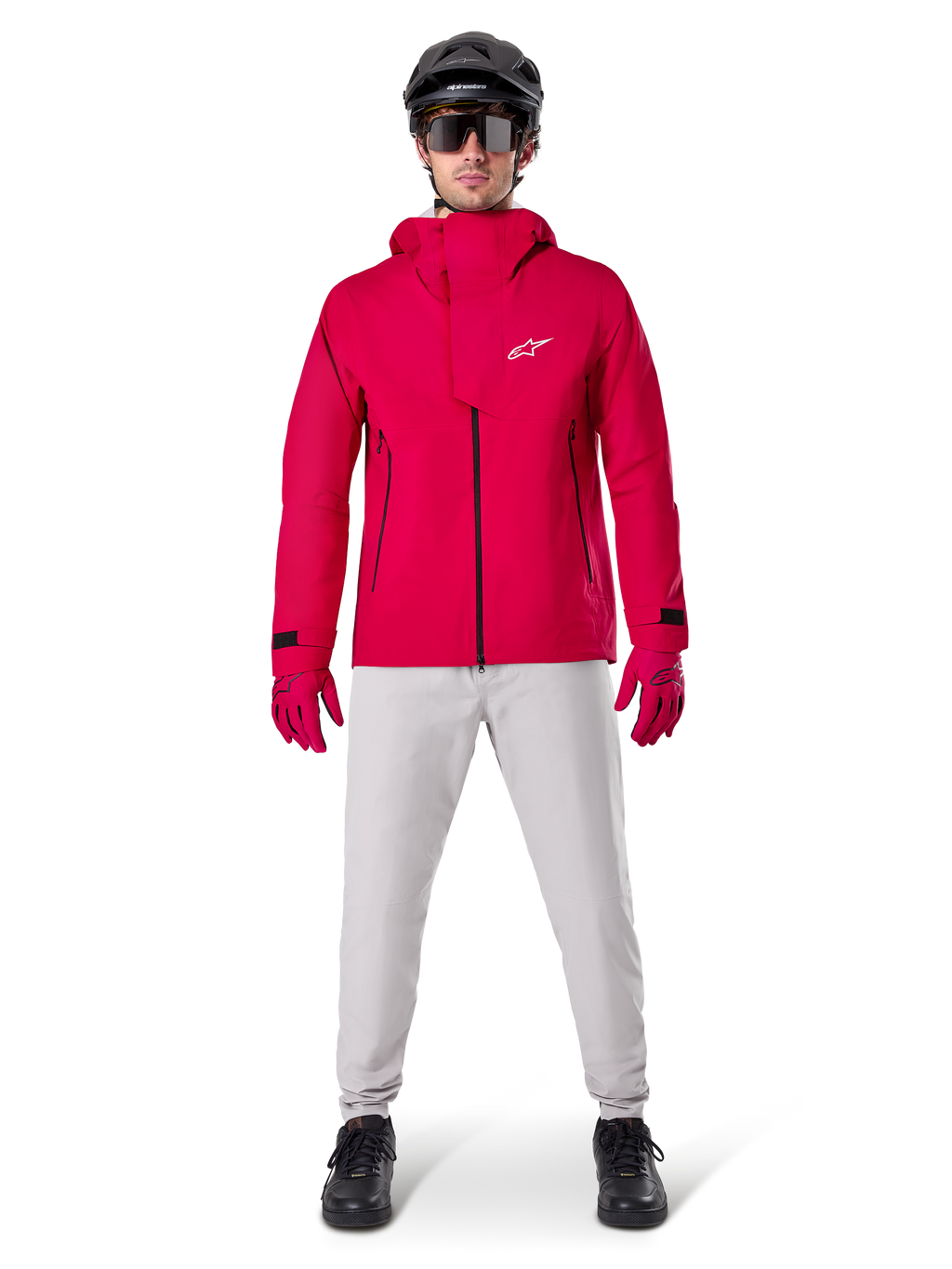 Alpinestars A-Dura Waterproof Pants, pantalones de MTB en color gris titanio, combinados con una chaqueta roja con capucha, guantes rojos y un casco negro de ciclismo de montaña, equipamiento ciclista impermeable profesional para condiciones de senderos húmedos