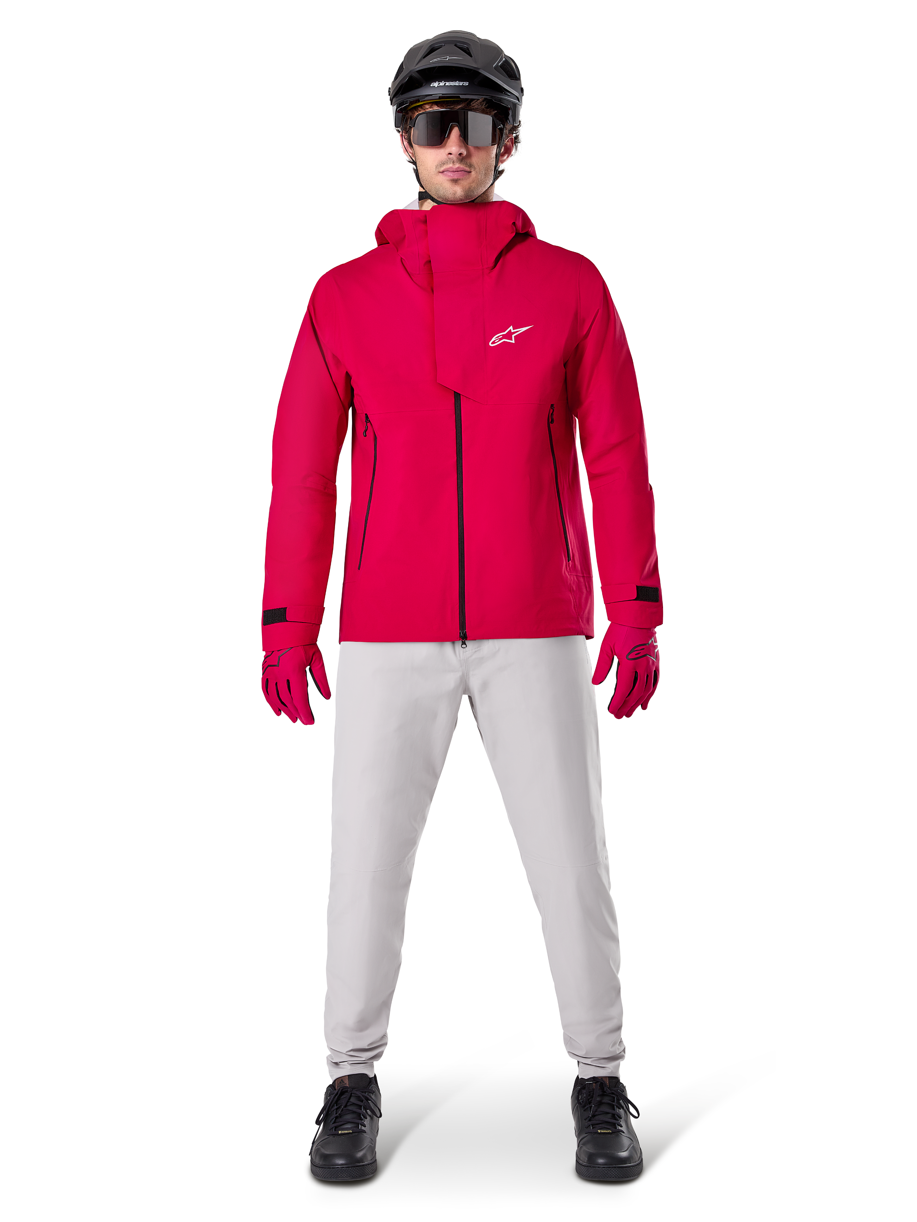 Alpinestars A-Dura Waterproof Pants, pantalones de MTB en color gris titanio, combinados con una chaqueta roja con capucha, guantes rojos y un casco negro de ciclismo de montaña, equipamiento ciclista impermeable profesional para condiciones de senderos húmedos