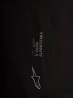 Detalle de pantalones Alpinestars A-Dura Ride negros, logotipos blancos y tejido elástico de alto rendimiento
