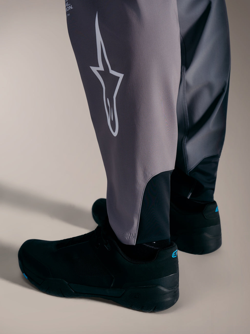 Pantalones A-Supra Elite grises con logotipo Astars blanco y puños elásticos para competición MTB de alto rendimiento.